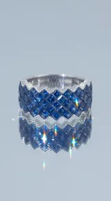 Anillo de plata 925 con diseño de banda ancha, engastado con múltiples circonias azules en un patrón geométrico entrelazado.