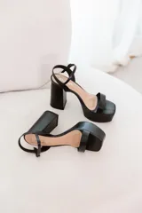 Sandalias de plataforma con taco ancho y alto, color dorado metálico. Poseen una tira ancha en la parte delantera del pie y una tira fina ajustable con hebilla en el tobillo.