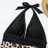 Malla entera combinada con parte superior lisa de color negro, escote halter cruzado y corpiño triangular con copas desmontables. Parte inferior de tiro alto con estampado animal print tipo leopardo.