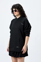 Canguro marrón con capucha, bolsillo frontal y puños ajustados. Estampa frontal con la palabra 'Dramatic' y gráfico en la espalda con tipografía bold y serpiente ilustrada.