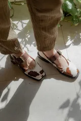 Zapatos tipo Mary Jane con punta cuadrada, confeccionados en cuero con estampado de vaca (animal print) y tira ajustable con hebilla metálica en color marrón.
