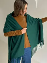 Ruana de tejido de punto en color verde esmeralda, con diseño envolvente y flecos en los extremos.