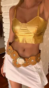 Cinturón ancho de cuero color marrón con apliques circulares con tachas plateadas y hebilla circular con detalle de guampa natural.