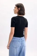 Top de punto color negro, de manga corta y corte ajustado con cuello redondo.
