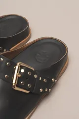 Zueco destalonado de cuero vacuno con estampado de leopardo. Presenta una tira ancha con hebilla metálica dorada sobre el empeine.