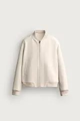 Cazadora bomber relaxed fit para hombre, confeccionada en tejido efecto ante de color beige. Presenta cuello, puños y dobladillo en rib elástico, bolsillos frontales de vivo y cierre central con cremallera.