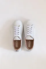 Championes blancos de cuero con cordones y suela de goma. Interior color beige y detalle plateado en el talón.