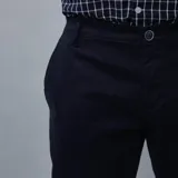 Pantalón de gabardina color azul marino, de corte ajustado y tiro medio, con cierre y botón frontal.