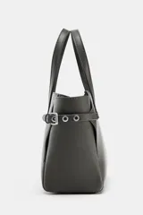 Bolso mini shopper de color gris oscuro, con diseño estructurado, doble asa de mano y correas laterales decorativas con hebillas metálicas. Incluye cierre magnético y compartimento interior con cremallera.