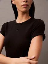 Vestido corto negro ajustado al cuerpo, de manga corta y cuello redondo. Presenta un pequeño logo bordado en el frente.