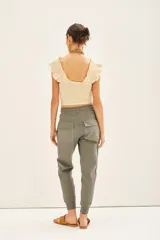 Pantalón tipo babucha de gabardina elastizada, color negro, con cintura elástica ajustable mediante cordón, puños en los tobillos, bolsillos diagonales frontales y bolsillos traseros con solapa y botón.