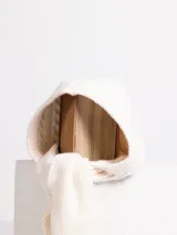Bufanda de punto gris con capucha integrada, diseñada con un tejido de textura suave y terminaciones en punta.