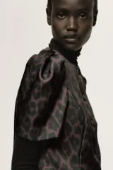 Blusa de sarga con estampado de leopardo, ajuste entallado, escote redondo, botones forrados frontales y mangas cortas abullonadas con pliegues en los hombros.