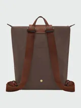 Mochila Longchamp de la línea Le Pliage Original, tamaño M, en color rosado con solapa y asas de cuero marrón.