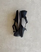 Mocasín negro de cuero vacuno, con punta cuadrada y detalle de borlas en el empeine.