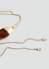 Collar largo de cadena fina dorada con dije colgante en forma de gota, combinación de metal dorado y resina en tono ámbar.