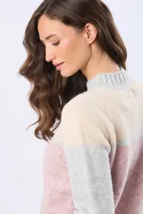 Buzo tejido de punto con diseño de bloques de color en tonos rosa, beige y gris. Presenta cuello redondo, mangas largas y corte holgado.