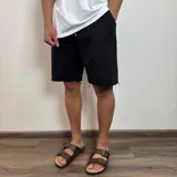 Short negro de algodón rústico con corte amplio y ruedo desflecado.