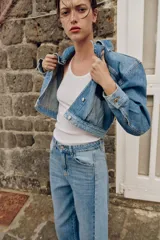 Cazadora corta de denim con cuello solapa y manga larga. Presenta un diseño de lavado combinado a contraste, con bolsillos de plastrón con solapa en el pecho y cierre frontal con botones metálicos.