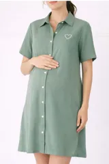 Camisa maternal color verde menta, de viscosa suave y liviana, con cuello camisero, mangas cortas y cierre frontal abotonado. Presenta un bolsillo con un corazón bordado en el pecho.