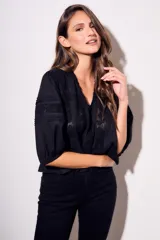 Blusa negra de algodón peinado con calce oversize, escote en V, mangas tres cuartos abullonadas y detalles de encaje y bordados en el frente y mangas.
