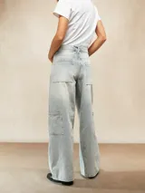Jean de corte wide leg en color celeste claro con lavado desgastado. Presenta un diseño de cinco bolsillos, incluyendo bolsillos laterales tipo cargo, cierre frontal con botón y bragueta, y costuras reforzadas en las piernas.