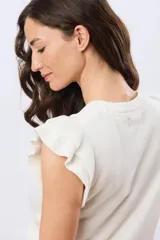 Remera tejida de algodón en color beige, de cuello redondo, sin mangas y con detalles de volados estructurados en los hombros.