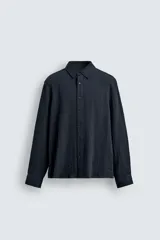Camisa de corte relajado confeccionada en tejido fluido con mezcla de viscosa. Presenta cuello solapa, cierre frontal con botones y manga larga con puños abotonados.