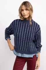 Sweater de tejido de punto con diseño de trenzas verticales, cuello alto y corte oversize. Presenta una textura marcada y puños acanalados.