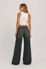 Pantalón de jean de tiro medio, corte ancho y diseño de perneras rectas con costuras frontales destacadas.