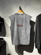 Musculosa gris unisex con efecto lavado desgastado, cuello redondo y la palabra 'Become.' bordada en rojo en el centro de la espalda.