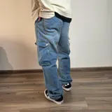 Pantalón tipo jean cargo de corte recto y tiro medio, en color azul claro lavado. Presenta bolsillos laterales con solapa y cierre de botón y cremallera.