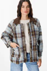 Chaqueta de corte holgado con estampado de cuadros en tonos beige, marrón y amarillo. Presenta cuello camisero en pana marrón, cierre frontal con botones y mangas largas con puños abotonados.