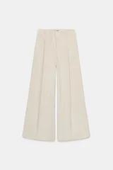 Pantalón de tiro medio confeccionado en tejido de pana, con diseño de pernera recta y holgada. Presenta pliegues frontales, cintura ajustable con lazada y cierre frontal con cremallera, botón y ganchos metálicos.