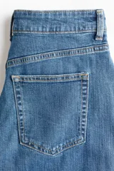 Jean de tiro alto confeccionado en denim de algodón con leve elasticidad. Presenta diseño de cinco bolsillos, cierre frontal con botón y cremallera, y perneras amplias de corte holgado con bajo deshilachado.