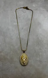 Collar con cadena tipo serpiente dorada y dije ovalado de la Virgen Milagrosa en tono dorado envejecido.