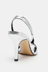 Sandalias plateadas de piel metalizada con puntera abierta, tiras cruzadas y cierre con tira trasera elástica. Tacón fino de 9,5 cm.