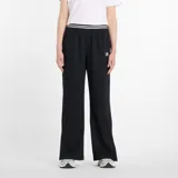 Pantalón deportivo ancho (wide leg) color negro, con cintura elástica a rayas blancas y un pequeño logo cuadrado de New Balance en la cadera.