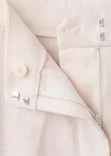 Pantalón de vestir de lino color beige, de corte recto y tiro medio, con trabillas, bolsillos laterales y bolsillos posteriores de ribete.