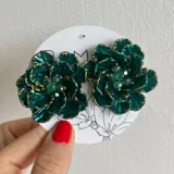 Par de aros con forma de flor color verde esmeralda con detalles dorados y cristales verdes en el centro.