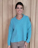 Sweater de tejido de punto color turquesa, con cuello en V y mangas largas de corte holgado.