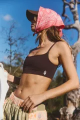 Top deportivo sin costuras, color marrón oscuro, con escote cuadrado y tirantes finos. Presenta un pequeño logo bordado en blanco en la parte inferior frontal.