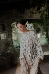 Buzo de tejido calado con diseño de red, de corte holgado y mangas largas con puños ajustados. Presenta un patrón de punto grueso en tonos jaspeados.