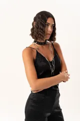 Top de satén negro con escote en V, decorado con detalles de encaje floral en el escote y en el ruedo. Presenta breteles finos ajustables y un corte asimétrico en la parte inferior.