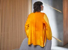 Chaqueta de lana merino afieltrada color naranja con teñido artesanal tie-dye, cuello alto que se prolonga como cinturón y bolsillos laterales.