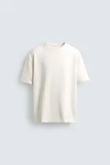 Camiseta de manga corta y cuello redondo, color blanco roto, con textura seersucker.