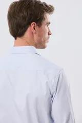 Camisa de vestir de manga larga con diseño de rayas finas celestes y blancas, cuello clásico y cierre frontal con botones. Incluye pequeño logo bordado en el pecho.