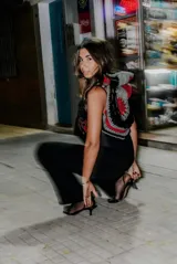 Chaleco negro de cuero con detalles de crochet en gris y rojo. Presenta un diseño sin mangas y un aplique de corazón bordado en el frente.