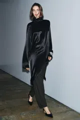Blusa de Zara Woman Collection confeccionada en viscosa, con cuello alto, manga larga y diseño asimétrico en el bajo. Presenta un acabado satinado y cierre en la espalda.