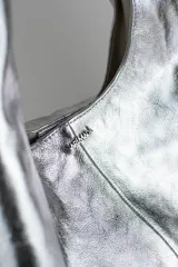 Cartera de cuero vacuno con pelo en diseño animal print similar a piel de ciervo, silueta triangular y asa integrada.